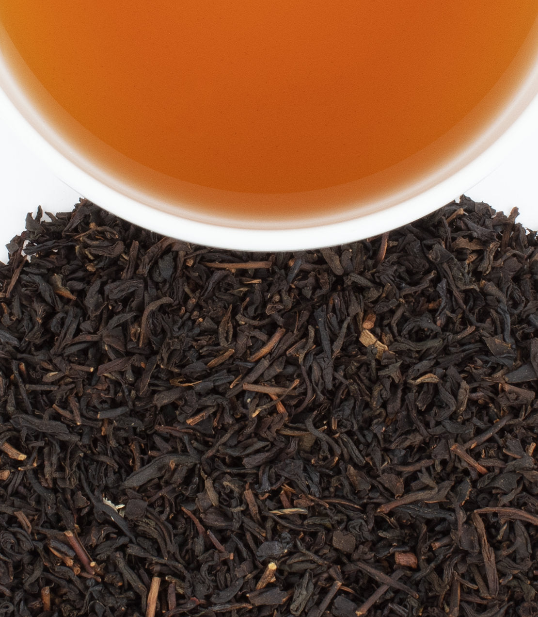 "Hallowe'en Party tea sachets with brewed tea in a cup and loose black tea leaves on a white background.