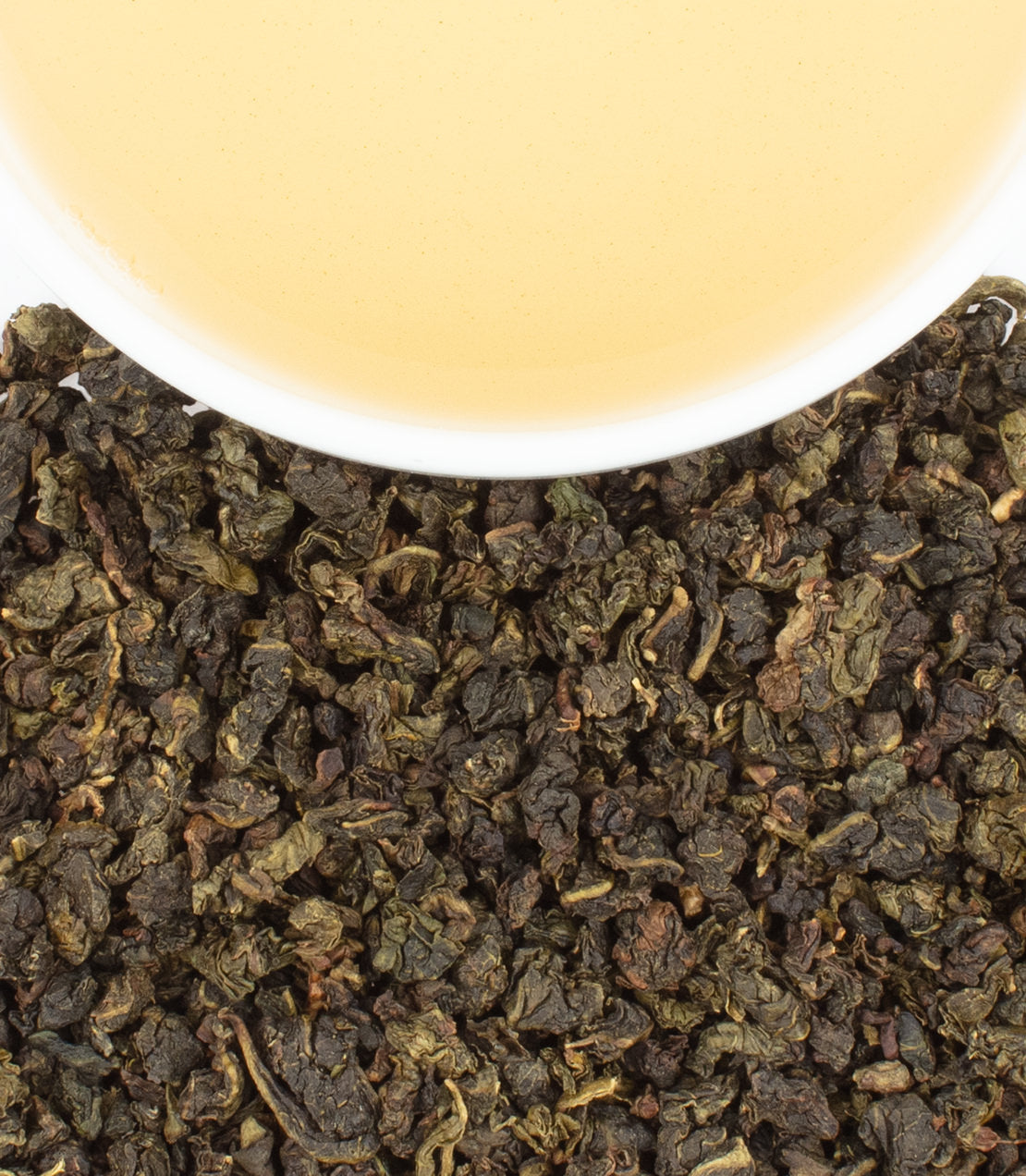 Coconut Lime Oolong tea sachets with brewed tea above loose leaves, showcasing rich colors and textures.