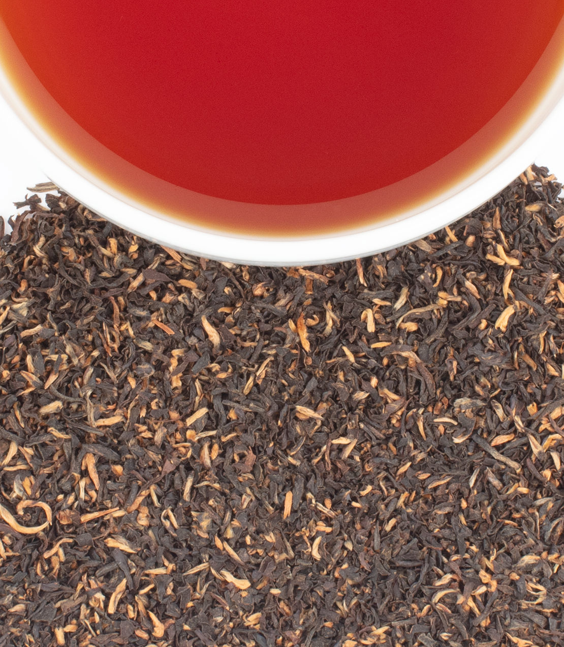 Harney & Sons Fine Teas- A close-up of Khongea Broken tea leaves with a cup of brewed tea above, showcasing rich color and texture.