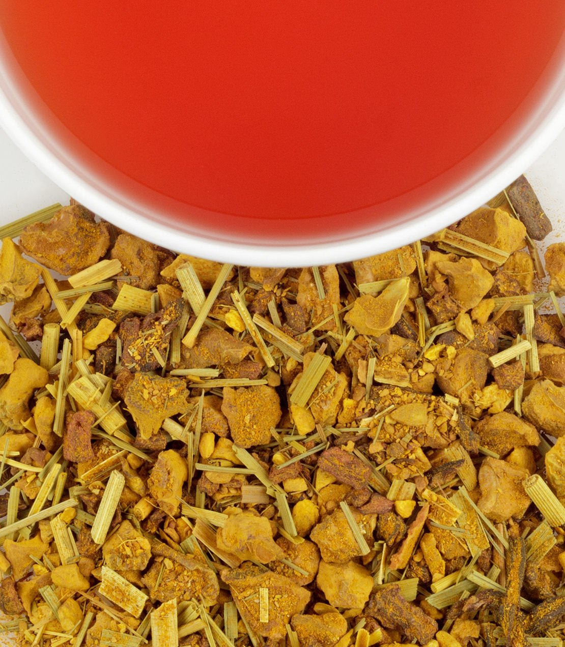 Organic Ginger Turmeric tea sachets in a tin, with dried ginger and turmeric pieces beside a cup of brewed tea.