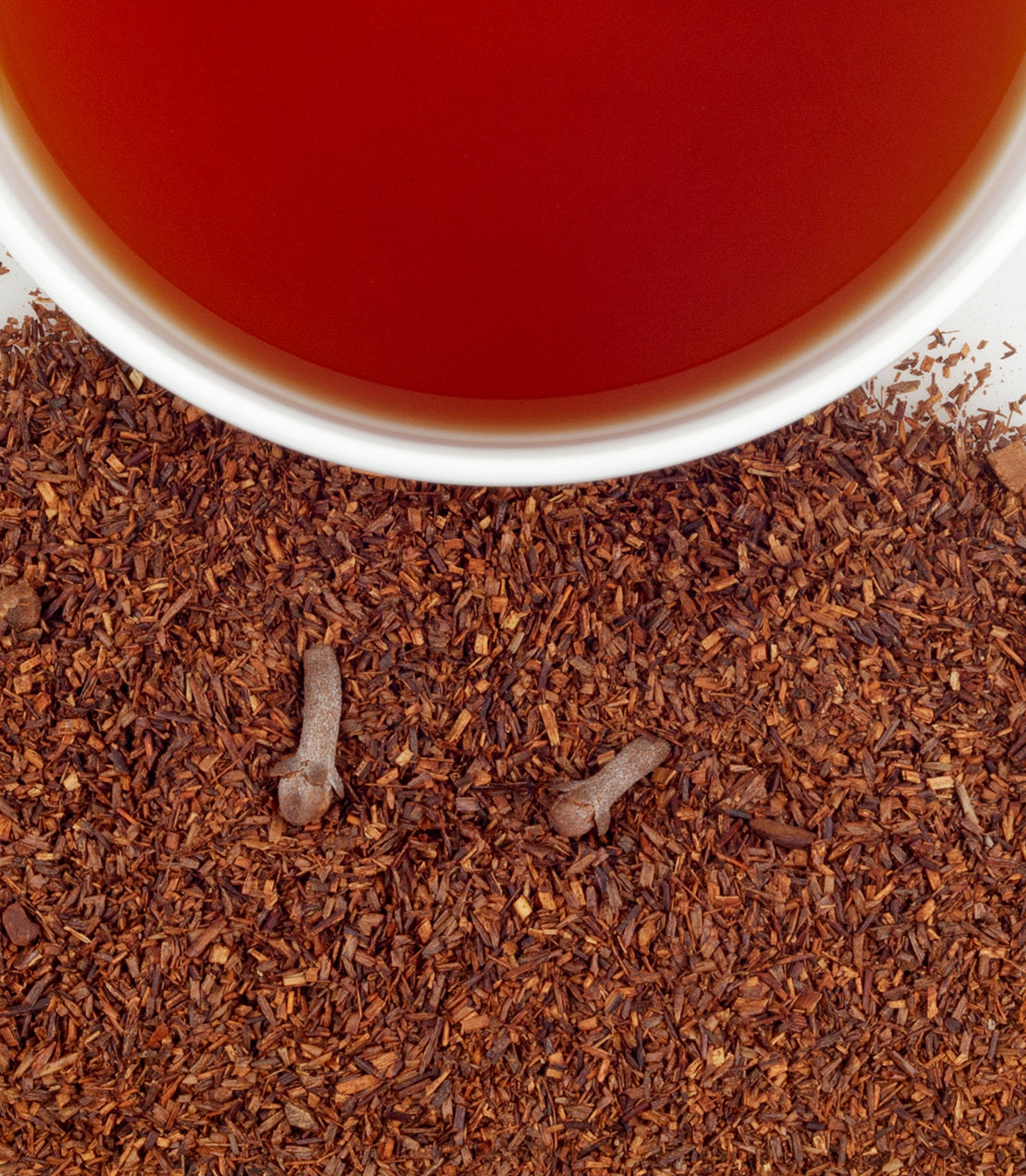 Pumpkin Spice tea sachets in a tin, with brewed tea and loose tea leaves scattered around.